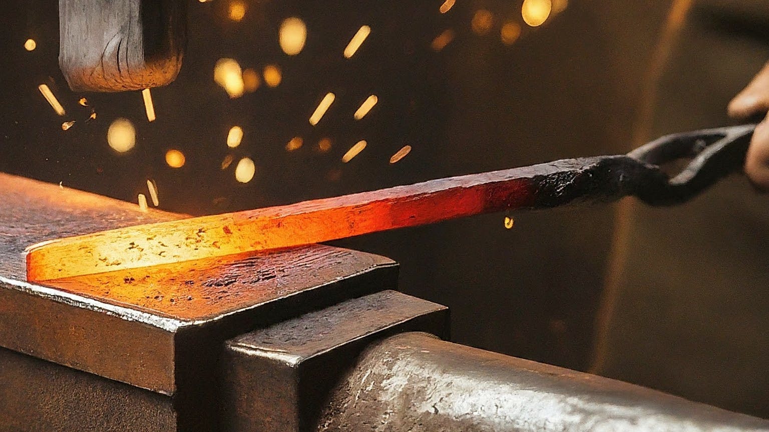 A metalworker hammering a red-hot piece of metal on an anvil.